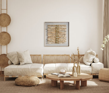Obraz z naturalnych patyczków w stylu boho na jasnej ścianie nad sofą w salonie urządzonym w stylu wabi sabi