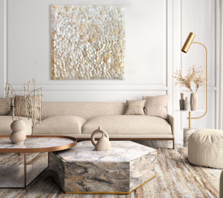 Obraz z masy perłowej na białej ścianie sztukateryjnej w eleganckim salonie w stylu japandi z beżową sofą, marmurowym stolikiem i złotą lampą